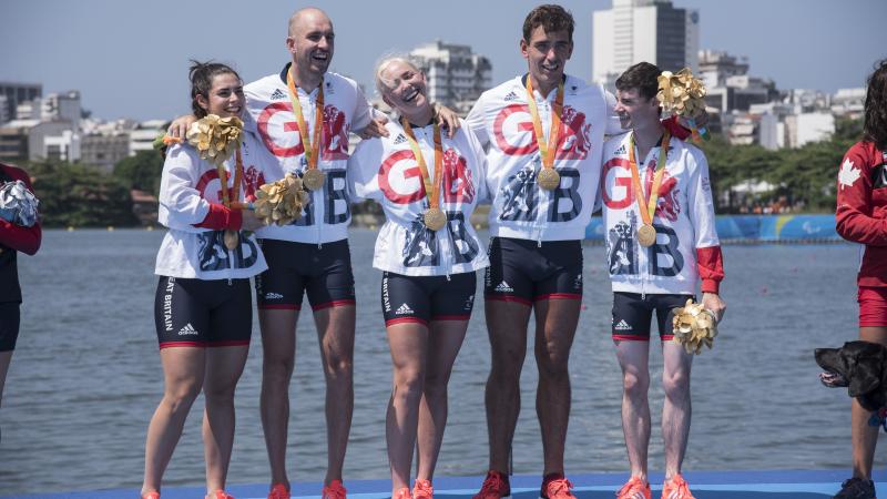 a group of five British Para rowers standing on the podium with their gold medals