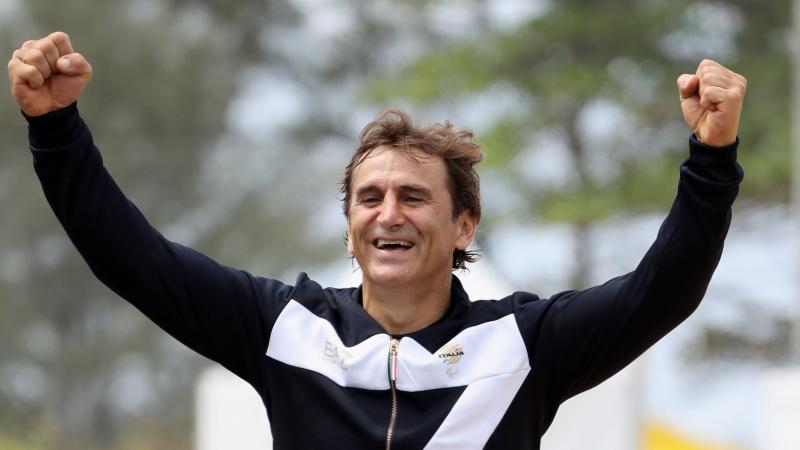 male Para cyclist Alex Zanardi raises his arms in celebration on the podium