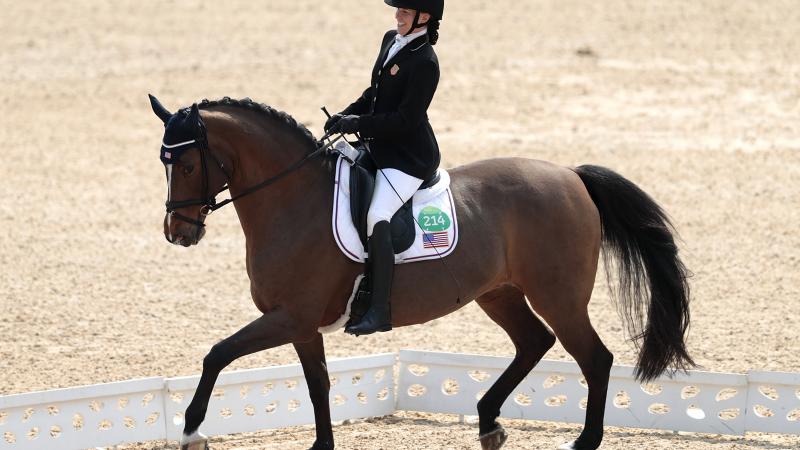 female Para equestrian rider Rebecca Hart competes on a horse in a dressage arena