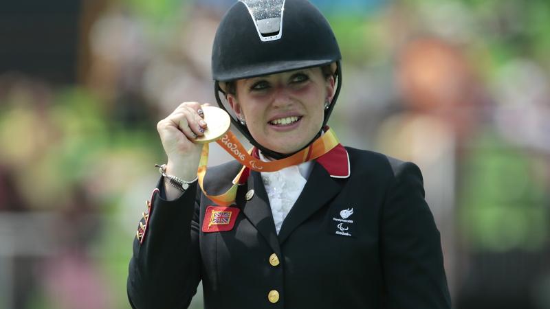 female Para equestrian rider Natasha Baker on the podium with her gold medal