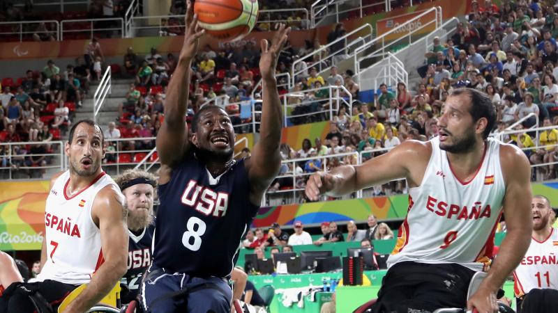 male wheelchair basketball players Alejandro and Pablo Zarzuela challenge a US player for the ball