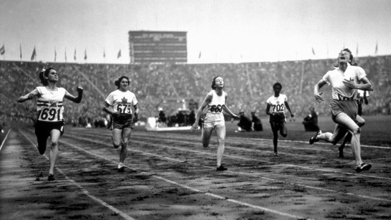 female sprinter Fanny Blankers-Koen crosses the finish line ahead of other female runners