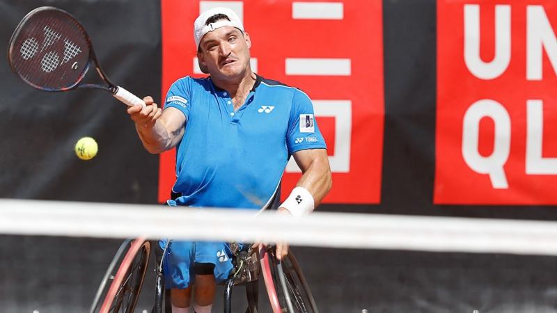 male wheelchair tennis player Gustavo Fernandez plays a forehand on a clay court