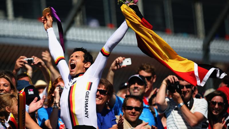 German Para cyclist Michael Teuber pumps his fist and celebrates with a German flag