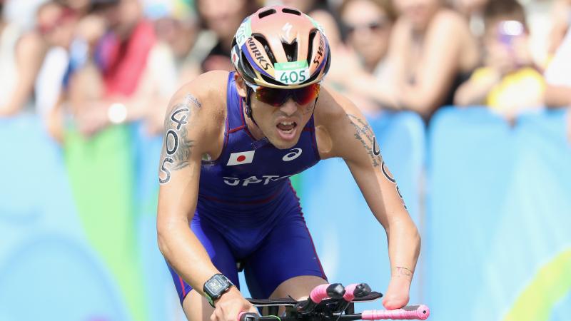 male Para triathlete Keiichi Sato racing on a bike