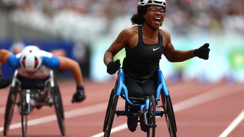 female wheelchair racer Kare Adenegan celebrates as she crosses the finish line