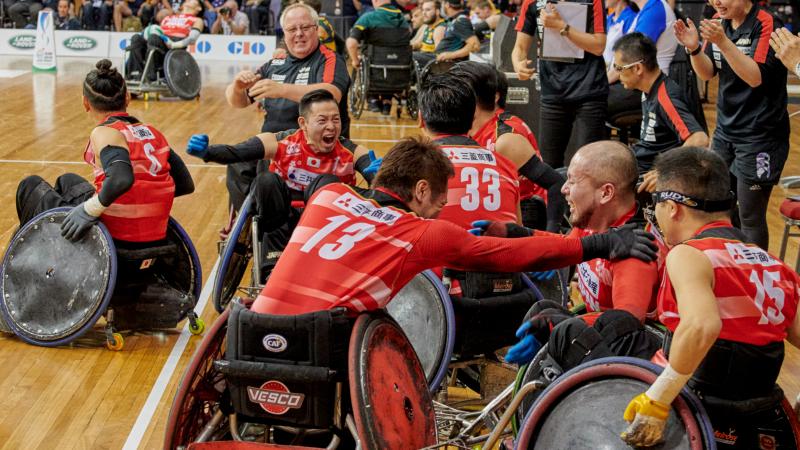 a group of Japanese wheelchair rugby players celebrate on the court