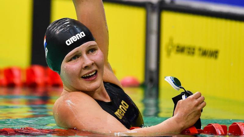 female Para swimmer Liesette Bruinsma raises her arm in celebration after winning her race