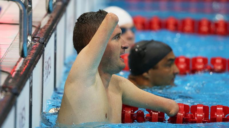 male Para swimmer Zsolt Vereczkei raises his arm in the water