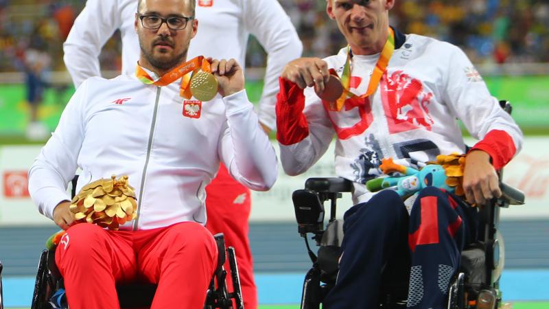 male Para athletes Stephen Miller and Maciej Sochal on the podium holding up their medals