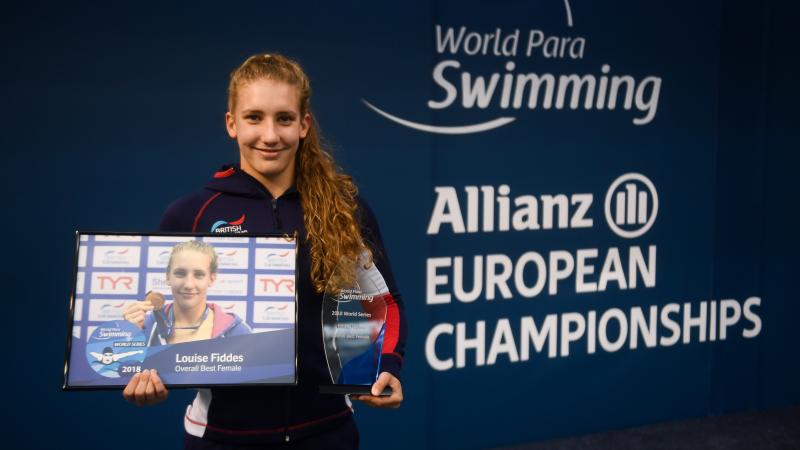 female Para swimmer Louise Fiddes smiling and holding two trophies