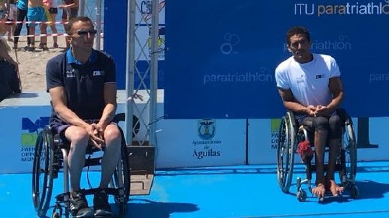 male Para triathletes Alexandre Paviza and Ahmed Andaloussi sitting on the podium