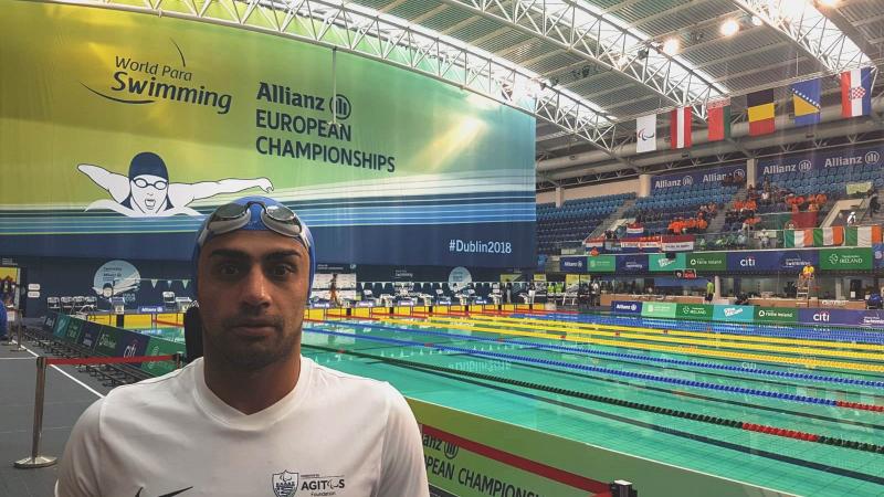 Man with swimming cap in front of a swimming pool
