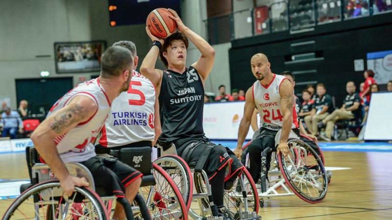 Man in wheelchair with a ball in his hands surrounded by other three men