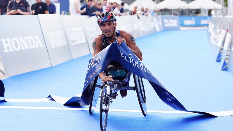 male Para triathlete Ahmed Andaloussi breaks the tape as he crosses the finish line