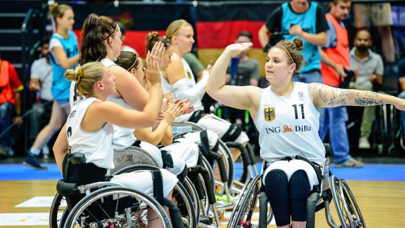 A female German wheelchair basketballer high fives her teammates