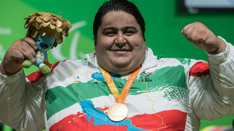 male powerlifter Siamand Rahman pumps his fist as he is wheeled onto the stage