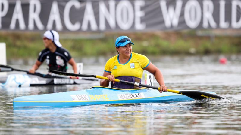 female Para canoeist Maryna Mazhula smiles in her boat after winning the race