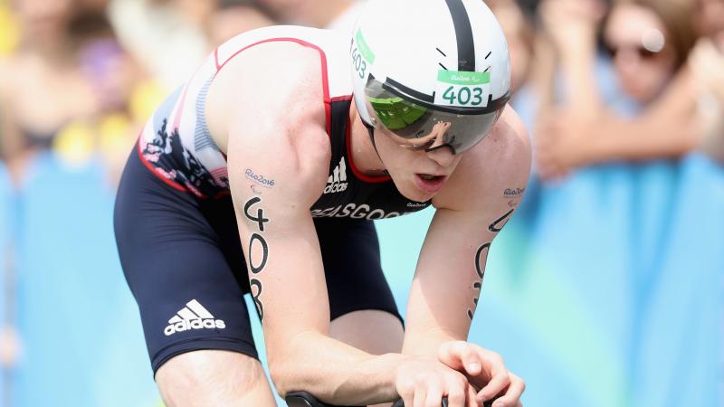 male Para triathlete George Peasgood rides on a bike