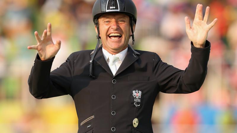 male Para equestrian rider Pepe Puch smiles and raises his hands in celebration