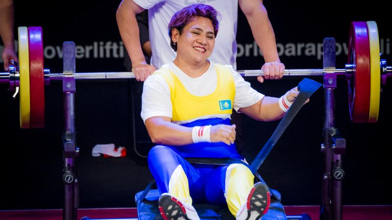 female powerlifter Raushan Koishibayeva sits on the bench and smiles