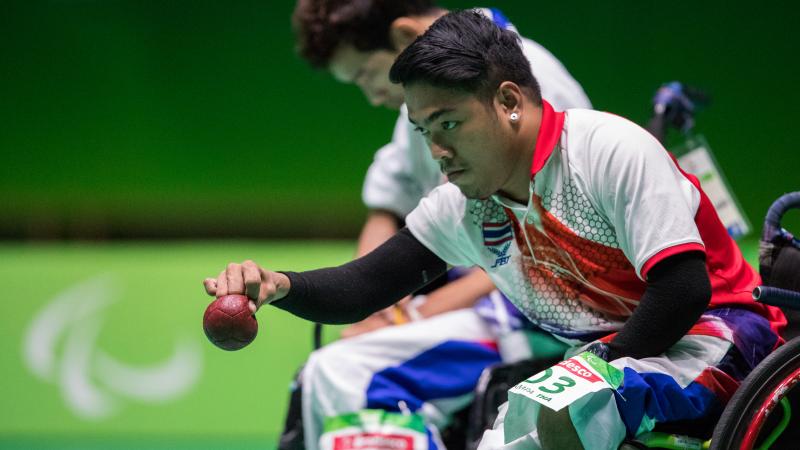 Man in a wheelchair throwing a red boccia ball