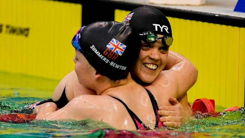 female Para swimmers Maisie Summers-Newton and Ellie Simmonds hug in the pool