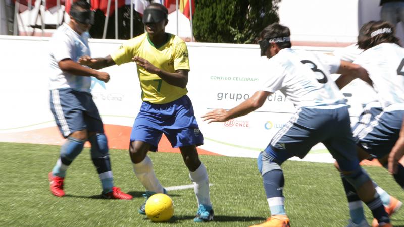 Brazilian vision impaired football dribbles the ball past Argentinian defenders