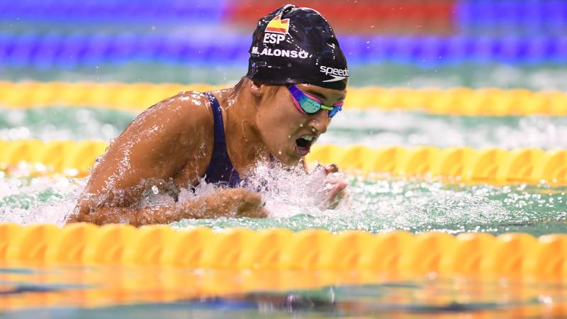 Woman swimming in the pool wearing a black cap with the Spanish flag