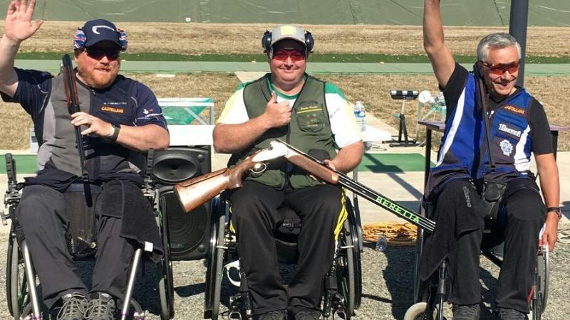 three male Para shooters in wheelchairs with Scottie Brydon in the middle waving to the crowd