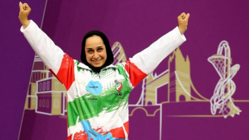 female Para shooter Sareh Javanmardi raises her arms on the podium