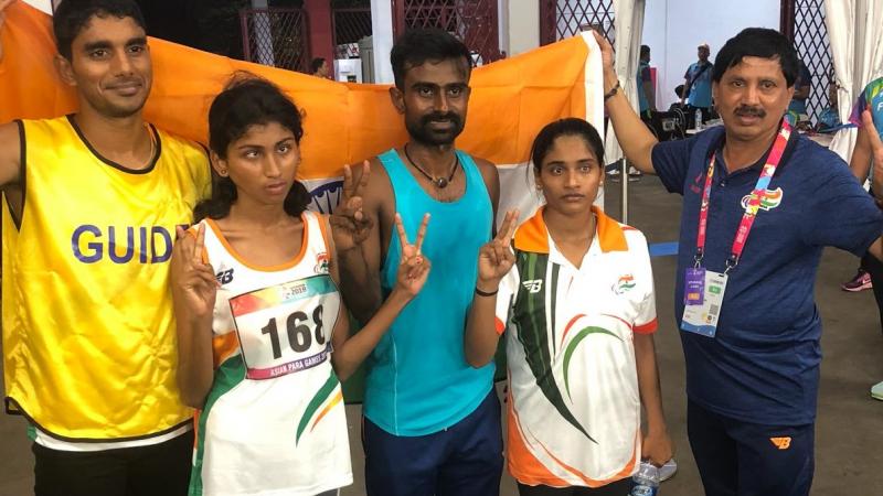 female Para athlete Rakshitha Raju standing with her guide in front of an India flag