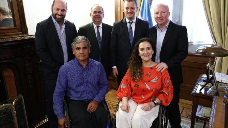 a group of people with Andrew Parsons at the centre in an official flag room