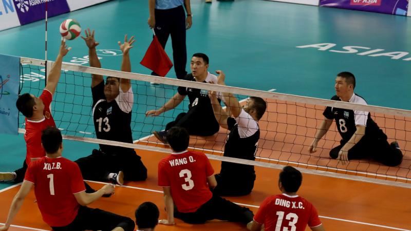 male sitting volleyball players from China and Kazakhstan volleying the ball over the net