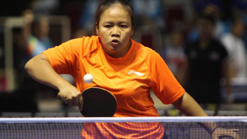 Woman in orange shirt playing table tennis