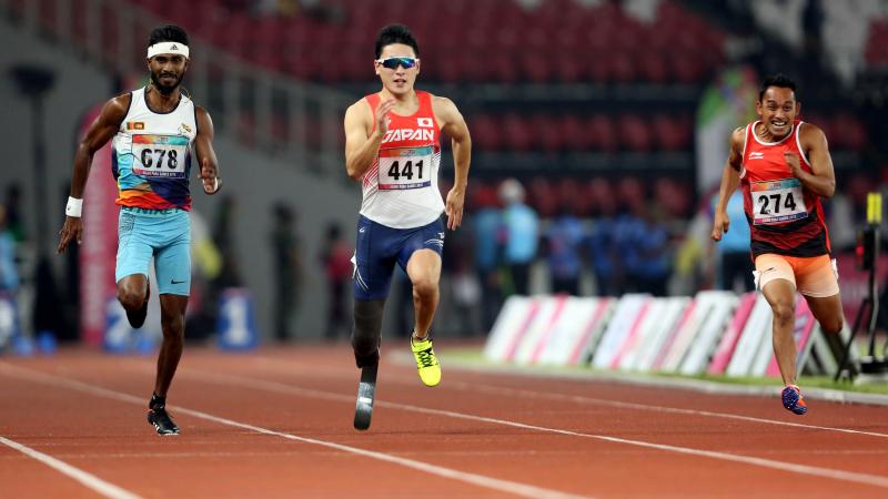 three male sprinters with Shunsuke Itani in the centre run down the 100m track