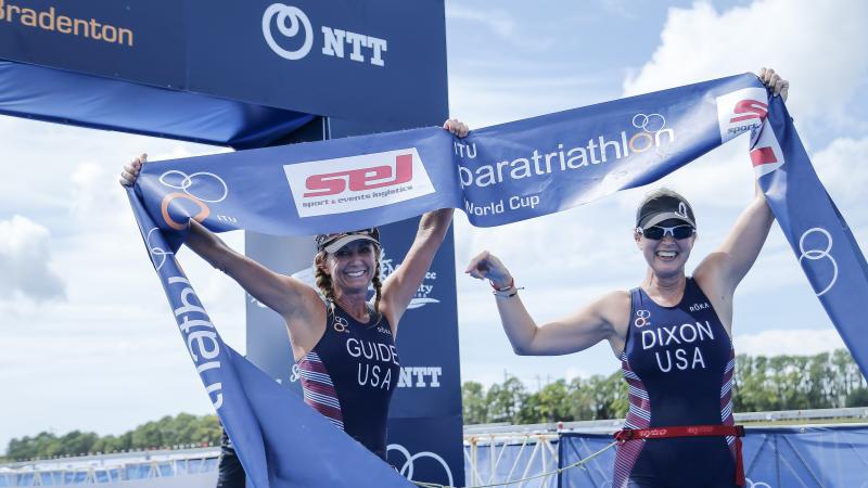 female Para triathlete Amy Dixon and her guide cross the finish line