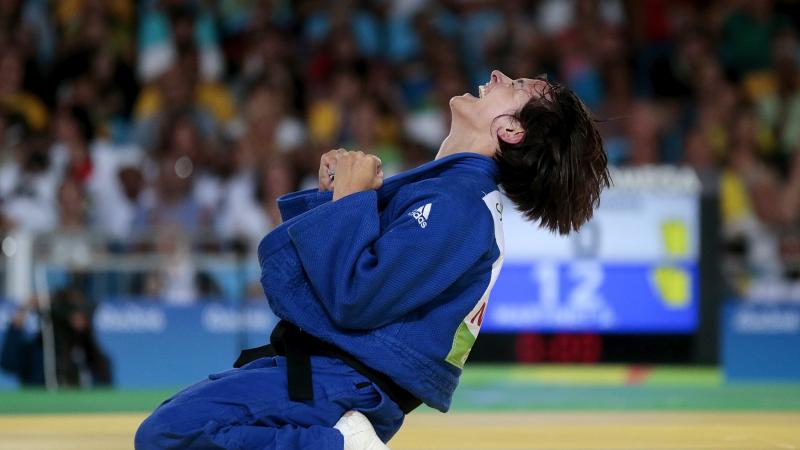 female judoka Sandrine Martinet sinks to her knees and clenches her fists after winning