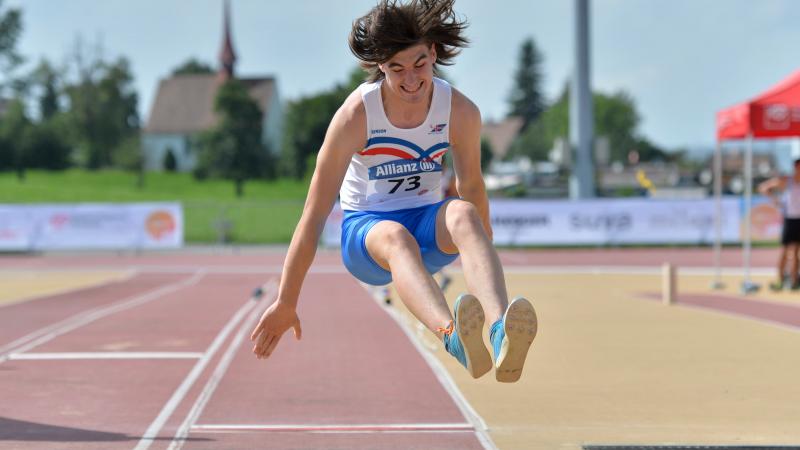 a male Para athlete jumps into a long jump sandpit