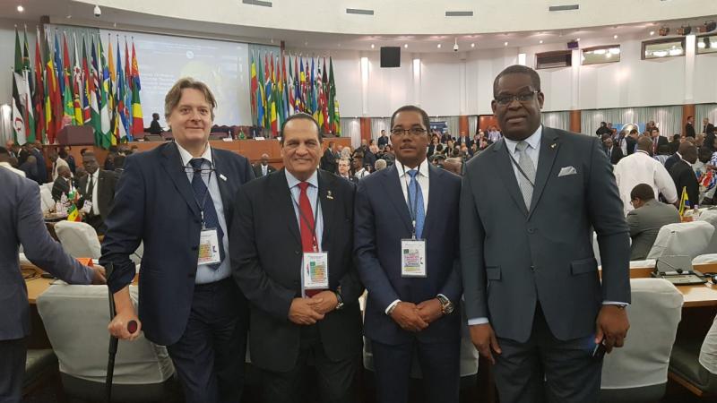 four men including Leonel da Rocha Pinto standing in suits in a conference hall