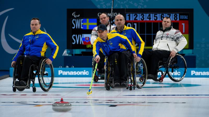 male wheelchair curler Viljo Petersson Dahl plays a stone on the ice