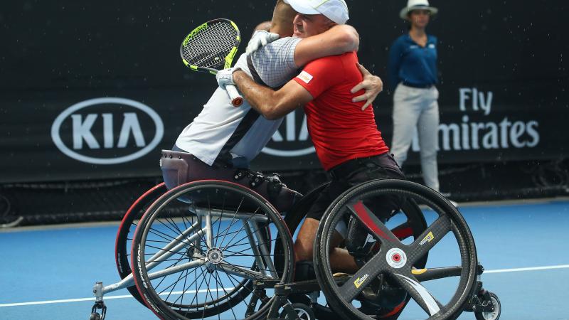 male wheelchair tennis players Stephane Houdet and Nicolas Peifer hugging on the court