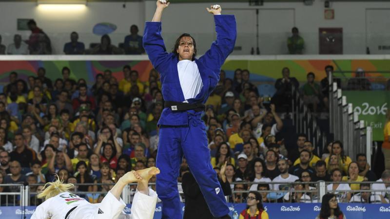 female judoka Naomi Soazo raises her arms straight up in the air in celebration