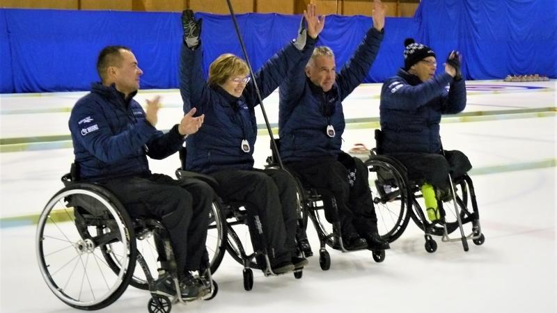 Four Estonian wheelchair curling athletes celebrate a shot on the ice sheet