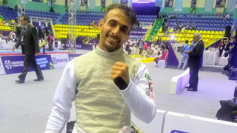 A man in a wheelchair wearing a fencing uniform