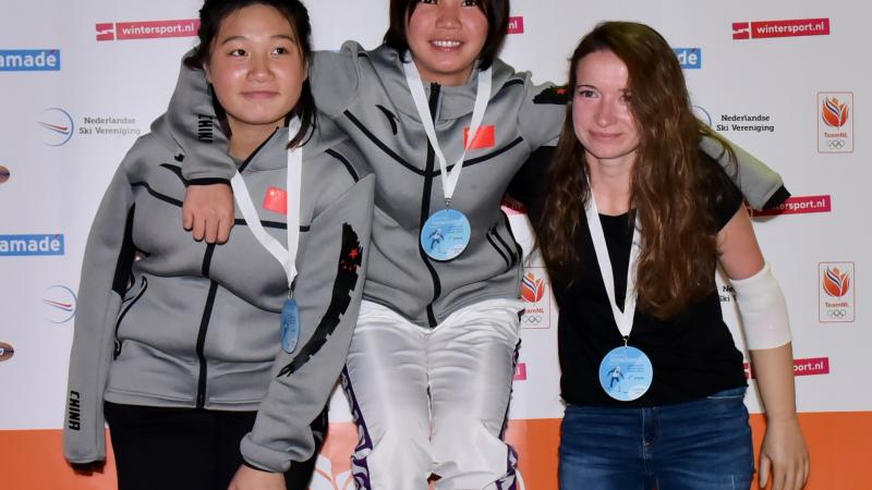 three female snowboarders standing on the podium with their arms around eachother
