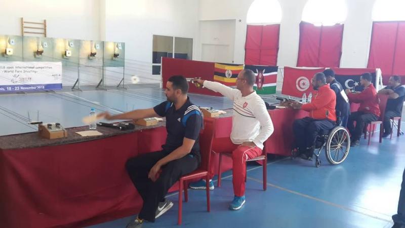 Five men competing in an indoor shooting event