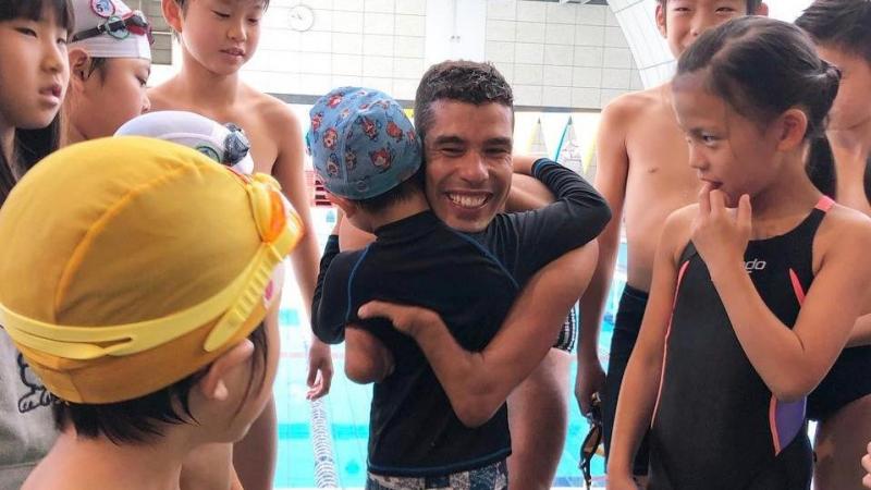 Daniel Dias - Tokyo A man hugging a child in the middle of a group of children