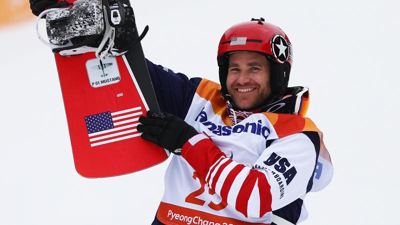 male Para snowboarder Mike Schultz holding up his snowboard