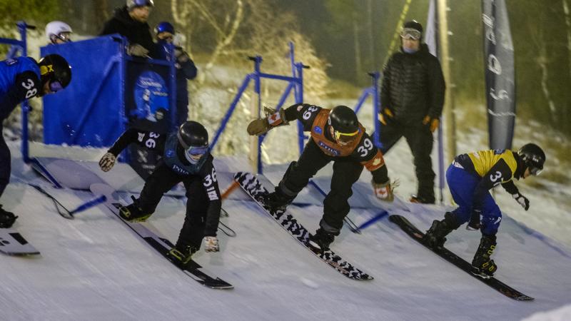 Four male snowboarders at the start gate for snowboard-cross